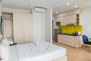 a bedroom with a white bed and a kitchen at Laurel Da Nang Apartment in Da Nang
