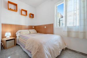 a white bedroom with a bed and a window at Estela in Sant Carles de la Ràpita