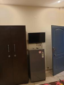 um quarto com uma televisão, um frigorífico e uma porta em OLD SCHOOL em Phagwara