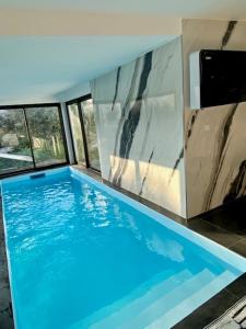 a large blue swimming pool in a house at Piscine et jacuzzi Loft ravissant dans une maison basque in Anglet