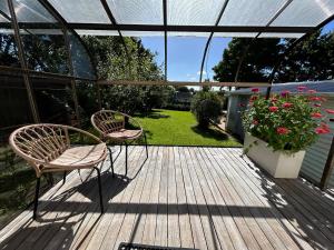 una terraza de madera con 2 sillas y una planta en Urban Kingsland Studio, en Auckland