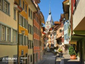 una calle estrecha con una torre de reloj en la distancia en Atemberaubende Triplexwohnung in der Altstadt Zug, en Zug