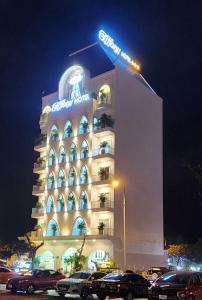 un edificio de hotel con coches estacionados frente a él en TIFFANY HOTEL & RESTAURANT en Phan Thiet