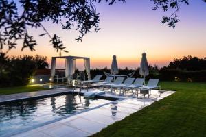 a pool with chairs and umbrellas in a backyard at Vilana Exclusive Villas in Skouloúfia