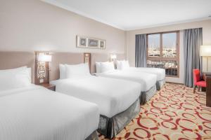 a hotel room with four beds and a window at Taiba Madinah Hotel in Medina