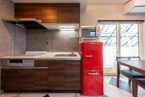 a red refrigerator in a kitchen with a sink at Furano Trailer Village Den in Furano +42 photos