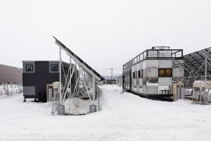 a train is sitting in the snow next to a building at Furano Trailer Village Den in Furano