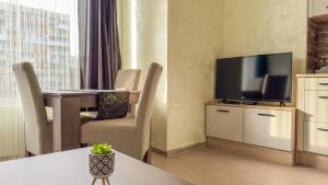 ein Hotelzimmer mit einem TV und einem Tisch mit Stühlen in der Unterkunft Апартамент Панчо in Sofia