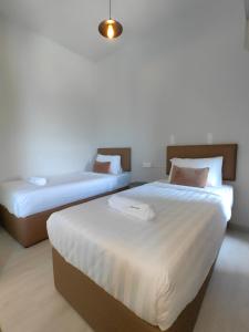 two beds in a room with white walls at Jesselton Quay by Miraton Lodge 2 in Kota Kinabalu
