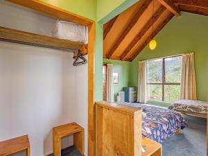 een slaapkamer met groene muren, een bed en een raam bij Mangawhero Tree House - Ohakune Holiday Home in Ohakune