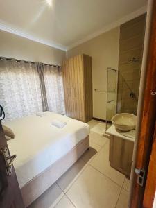 a bedroom with a bed and a bathroom with a sink at Bluewave Lifestyle Villa in Hartbeespoort