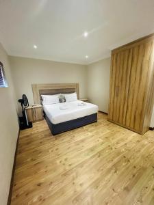 1 dormitorio con 1 cama y suelo de madera en Bluewave Lifestyle Villa, en Hartbeespoort