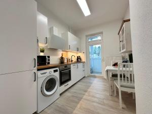 uma cozinha branca com uma máquina de lavar roupa e uma mesa em TOP Altbauwohnung in Kiel Mitte em Kiel
