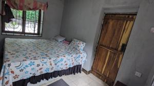 1 dormitorio con 1 cama y puerta de madera en Tripple H rent House en Kilindoni