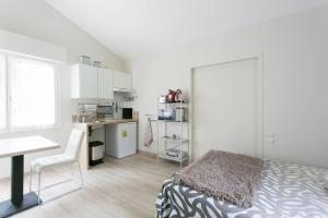 um quarto com uma cama, uma secretária e uma cozinha em studio lumineux au calme em Gif-sur-Yvette