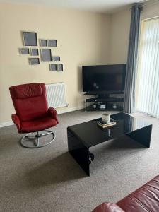 a living room with a red chair and a coffee table at Hatley Residencies in Dudley