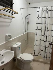 a bathroom with a toilet and a shower curtain at Caishen Modern Affordable Apartelle 202 in Silang