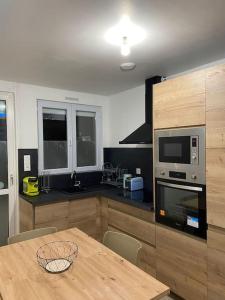 a kitchen with a wooden table and a microwave at Les Cèdres in Morbier