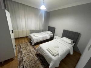 una camera con 2 letti, lenzuola bianche e un tappeto di Geniş aileler için ideal daire a Istanbul