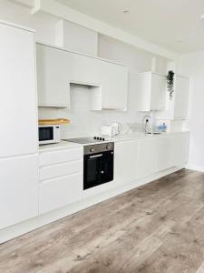 a white kitchen with white cabinets and a sink at Coastal Luxury Home in Margate in Margate