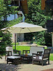 three chairs and a table with an umbrella at Chamkoria Chalets in Borovets