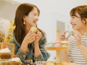 Duas mulheres sentadas numa mesa a comer queques. em AMAZING LIFESTYLE GLAMPING HOTEL - Vacation STAY 43987v em Nagahama