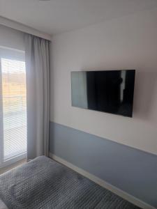 um quarto com uma televisão numa parede branca em Apartament Kołobrzeg Aqua Polanki em Kolobrzeg