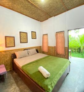 een slaapkamer met een bed met een groene deken bij Kembang Kuning Cottages in Tetebatu
