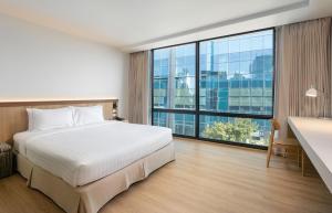 Cette chambre comprend un lit et une grande fenêtre. dans l'établissement VIC 3 Bangkok Hotel, à Bangkok
