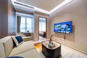 Una sala de estar con un sofá y un televisor en una pared. en 岗厦汇花园行政公寓酒店-深圳福田会展中心岗厦地铁站店, en Shenzhen