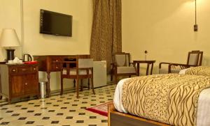 a hotel room with a bed and a desk and a television at Vijay Vilas Heritage Resort in Lāeja