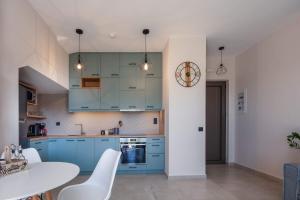 a kitchen with blue cabinets and a table and chairs at New Modern Villas with Private Pools and Walking distance to Beach in Panormos Rethymno +82 photos