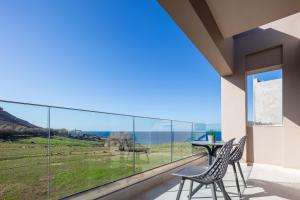 a balcony with two chairs and a table with a view at New Modern Villas with Private Pools and Walking distance to Beach in Panormos Rethymno