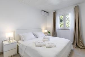 a white bedroom with two beds and a window at Seafront House on Island Korčula in Korčula
