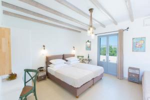 a white bedroom with a bed and a balcony at Ampelos Plaka in Plaka