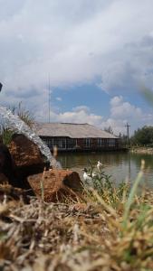 a water fountain in front of a building next to a lake at The Gaia House Magaliesburg in Magaliesburg