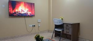 a room with a fireplace and a chair and a tv on the wall at Serene Studios Kamakis Eastern bypass in Ruiru