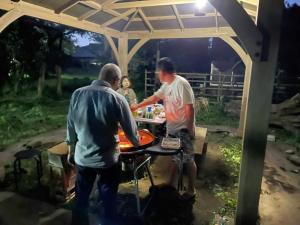 two men cooking food on a grill at a picnic table at Glamp House HANANOMORI - Vacation STAY 12585 in Yotsukaidō