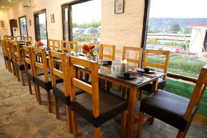 uma sala de jantar com uma longa mesa de madeira e cadeiras em Corbett Tiger Retreat em Rāmnagar