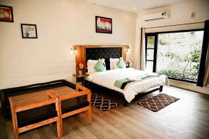 a bedroom with a bed and a desk and a window at Corbett Tiger Retreat in Rāmnagar