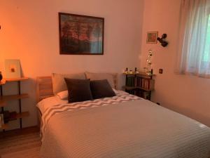 1 dormitorio con 1 cama blanca grande con almohadas negras en Dömös Cube - kiadó nyaraló kilátással a Dunakanyarra en Dömös