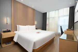 a bedroom with a large white bed and a window at Yzhi Hotel - West Sports Road Metro Station in Guangzhou
