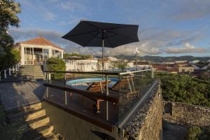 a patio with an umbrella and chairs and a pool at Quinta das Rosas Villas in Ribeira Grande