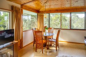 a dining room with a table and chairs and windows at Volcano Inn Bed n Breakfast in Volcano