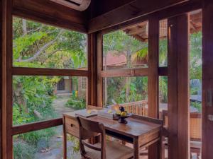 a dining room with large windows and a wooden table at Berlima Wooden Lodge by Pramana Villas in Ubud