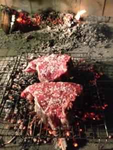 Agriturismo Il Macchione في بينزا: قطعتين من اللحوم الطبخ على شواية