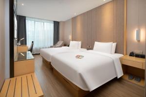 a large white bed in a hotel room at Yzhi Hotel - West Sports Road Metro Station in Guangzhou