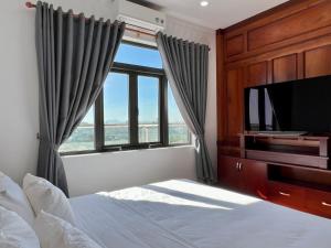 a bedroom with a bed and a tv and a window at Đoàn Gia Luxury House in Pleiku