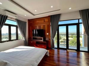 a bedroom with a bed and a tv and windows at Đoàn Gia Luxury House in Pleiku