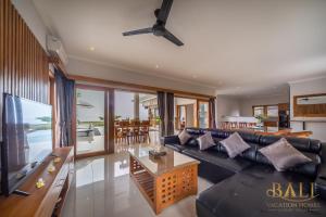 sala de estar con sofá de cuero negro y mesa en Premium 4BR Villa + Private Pool +Ocean view! en Tegallengah